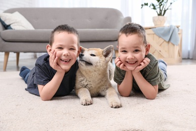 Photo of Happy boys with Akita Inu dog on floor in living room. Little friends