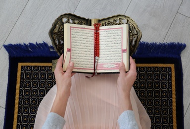 Photo of Muslim woman reading Koran indoors, top view