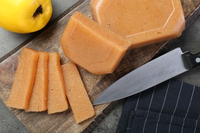 Photo of Tasty sweet quince paste, fresh fruit and knife on grey table, flat lay