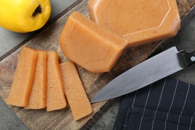 Tasty sweet quince paste, fresh fruit and knife on grey table, flat lay