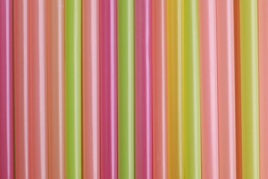 Photo of Colorful plastic straws as background, top view