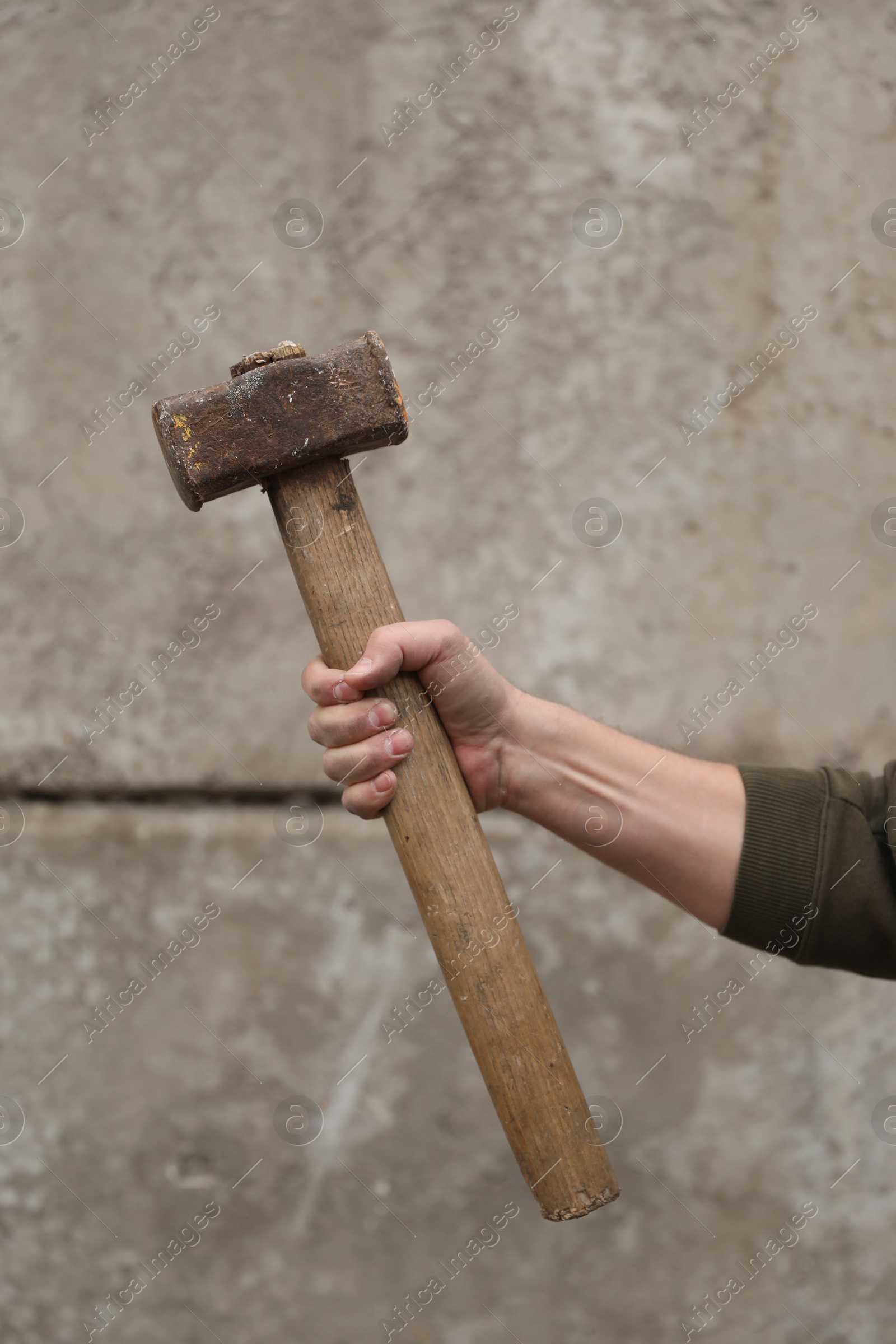 Photo of Man with sledgehammer near grey wall, closeup