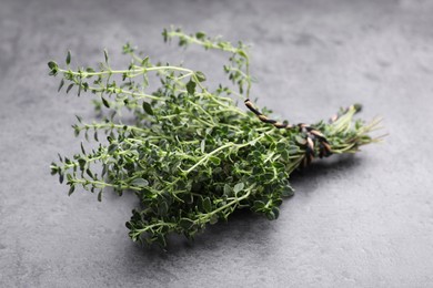 Photo of Bunch of aromatic thyme on grey table, closeup. Fresh herb