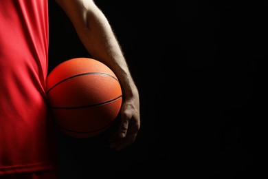 Photo of Basketball player with ball on black background, closeup. Space for text
