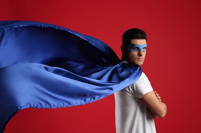 Photo of Man wearing superhero cape and mask on red background