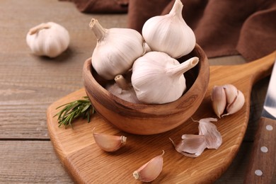 Photo of Fresh garlic and knife on wooden table, closeup. Space for text