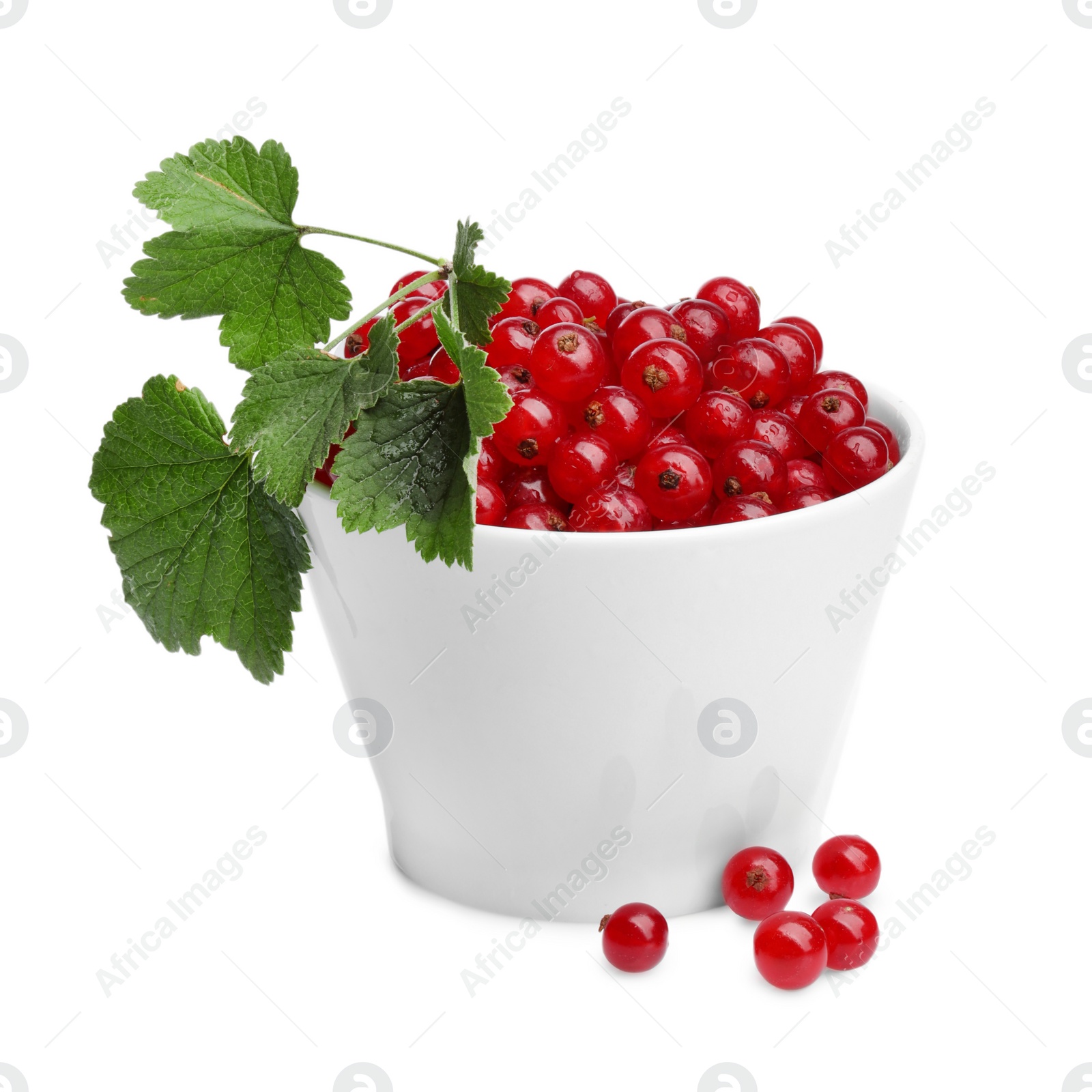 Photo of Tasty ripe redcurrants and green leaves in bowl isolated on white