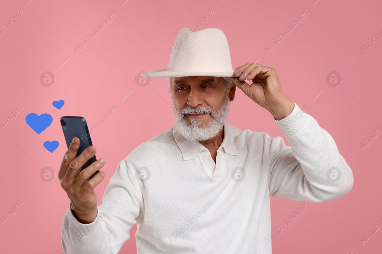 Image of Long distance love. Man video chatting with sweetheart via smartphone on pink background. Hearts near device