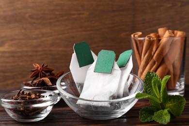 Tea bags and ingredients on wooden table, closeup