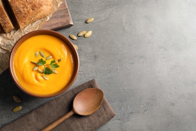 Photo of Flat lay composition with pumpkin cream soup in bowl on gray background. Space for text