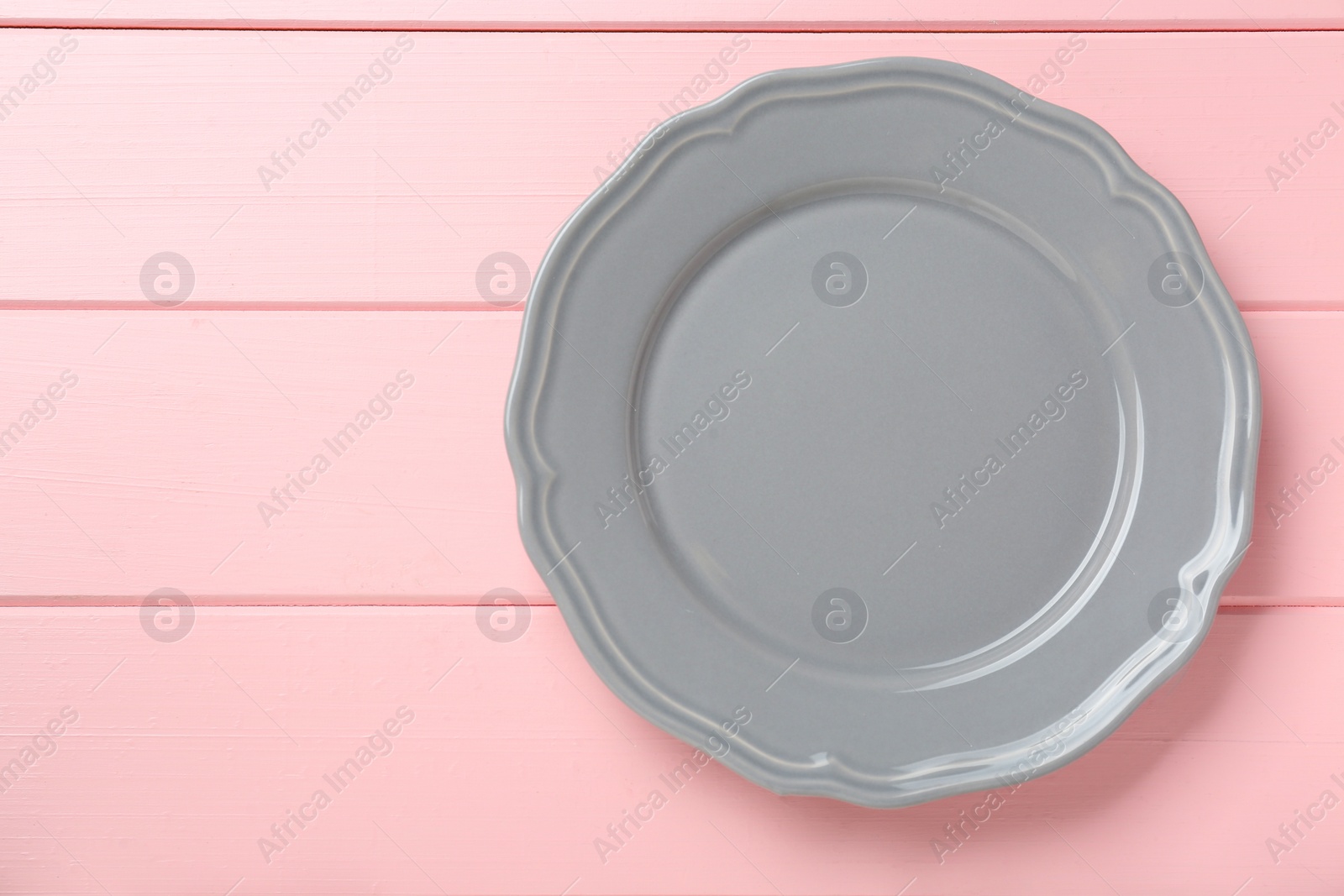 Photo of Empty grey ceramic plate on pink wooden table, top view. Space for text