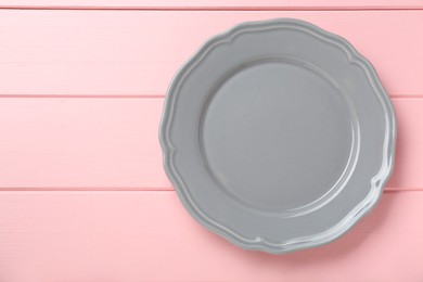 Empty grey ceramic plate on pink wooden table, top view. Space for text
