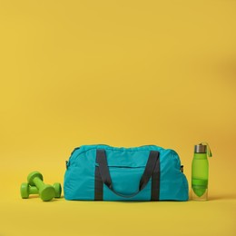 Photo of Blue gym bag and sports accessories on yellow background