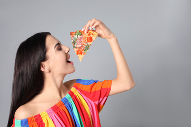 Photo of Beautiful woman with pizza on grey background, space for text