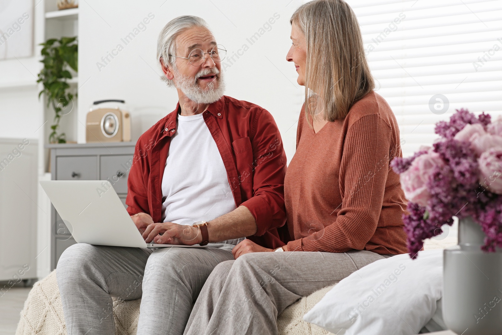 Photo of Senior couple using laptop on sofa at home