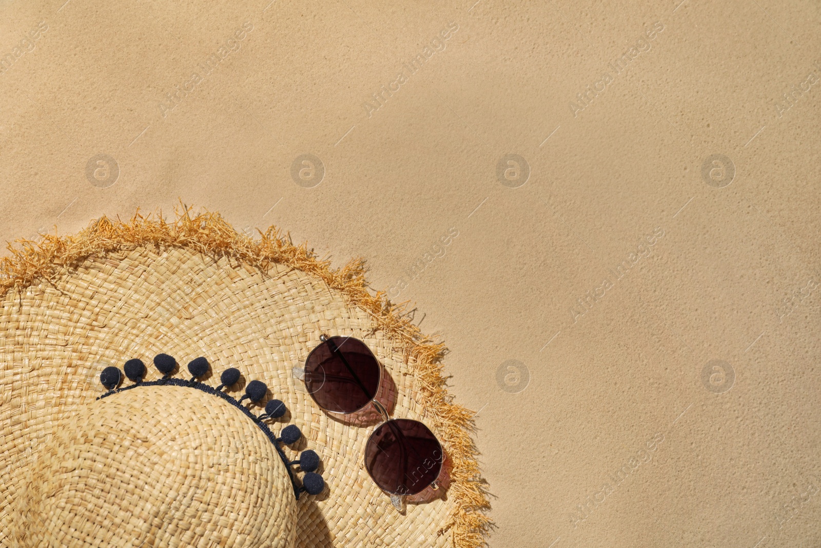 Photo of Flat lay composition with hat and sunglasses on sand, space for text. Beach objects