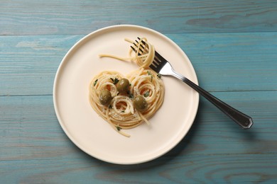 Photo of Heart made of tasty spaghetti, fork, olives and cheese on light blue wooden table, top view