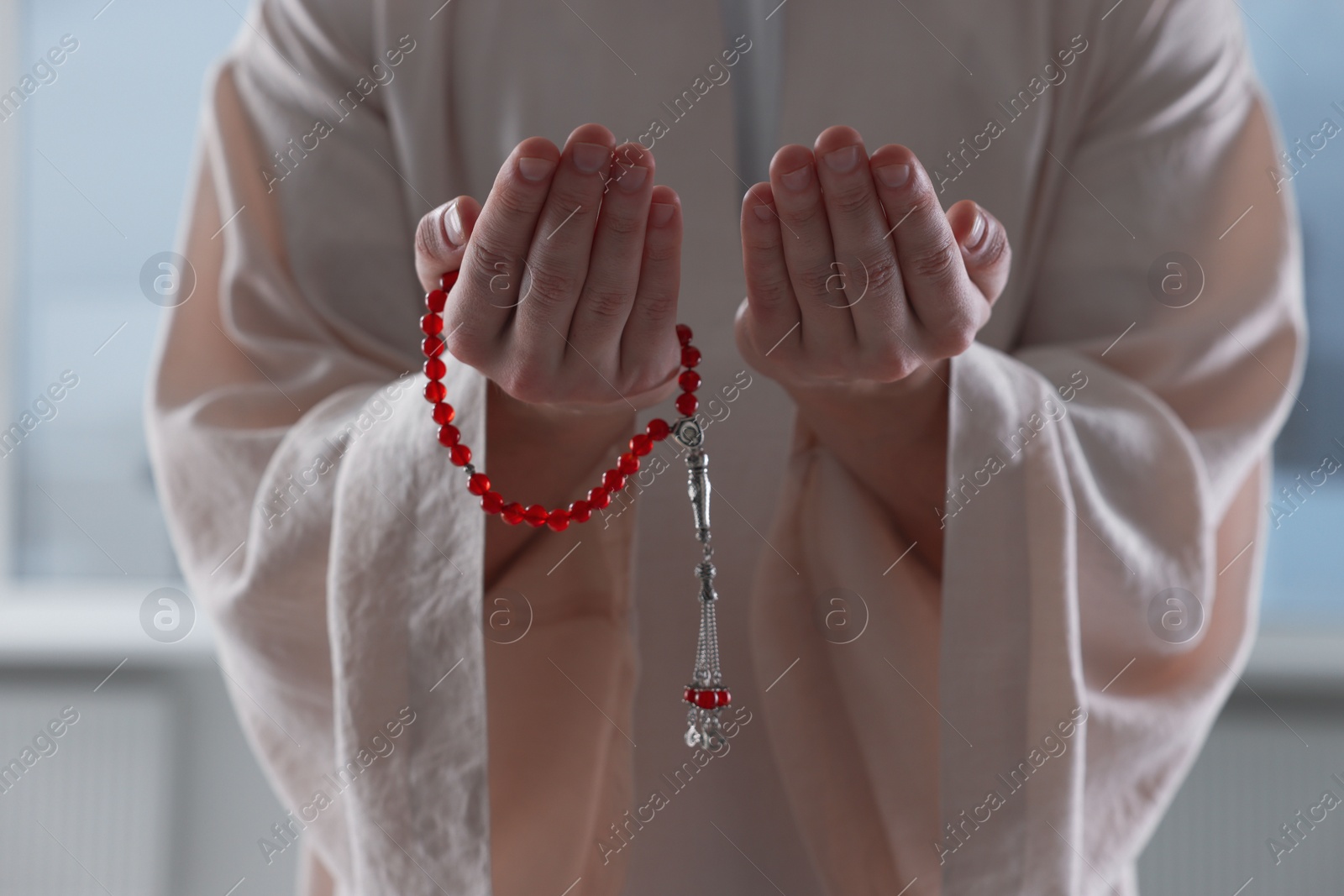 Photo of Muslim man with misbaha praying indoors, closeup