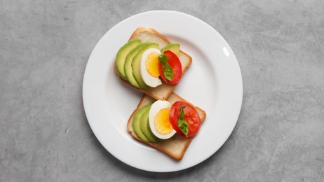 Photo of Tasty sandwiches with boiled egg, avocado and tomato on grey table, top view