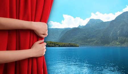 Image of Woman opening red front curtain and picturesque view of river and mountains on background