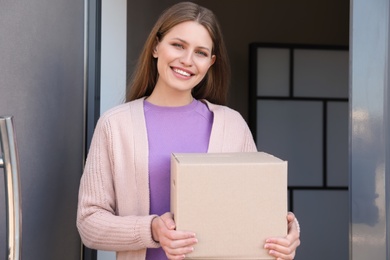 Photo of Portrait of smiling woman with parcel at door, mockup for design. Delivery service