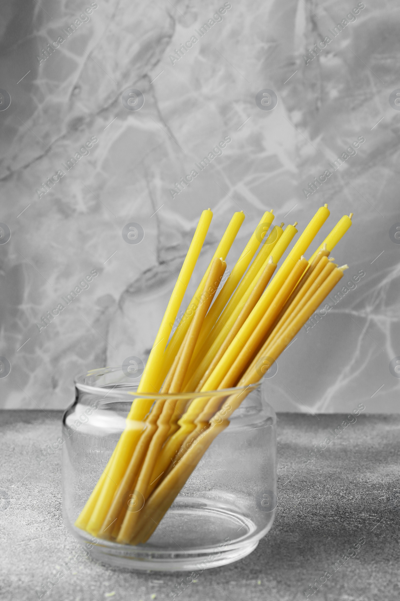 Photo of Many church candles on grey textured table