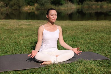 Beautiful woman practicing yoga on mat outdoors. Lotus pose