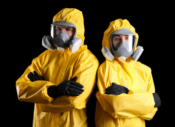 Photo of Man and woman wearing chemical protective suits on black background. Virus research