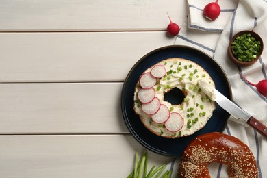 Photo of Delicious bagel with cream cheese, green onion and radish on white wooden table, flat lay. Space for text