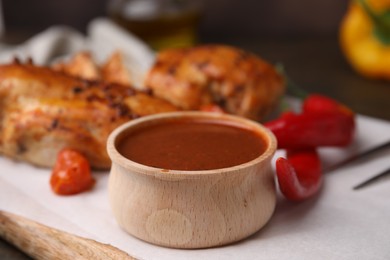 Photo of Baked chicken fillets and marinade on wooden table, closeup