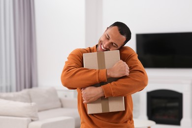 Photo of Happy young man with parcel at home. Internet shopping