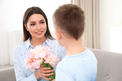 Photo of Little son congratulating his mom at home. Happy Mother's Day