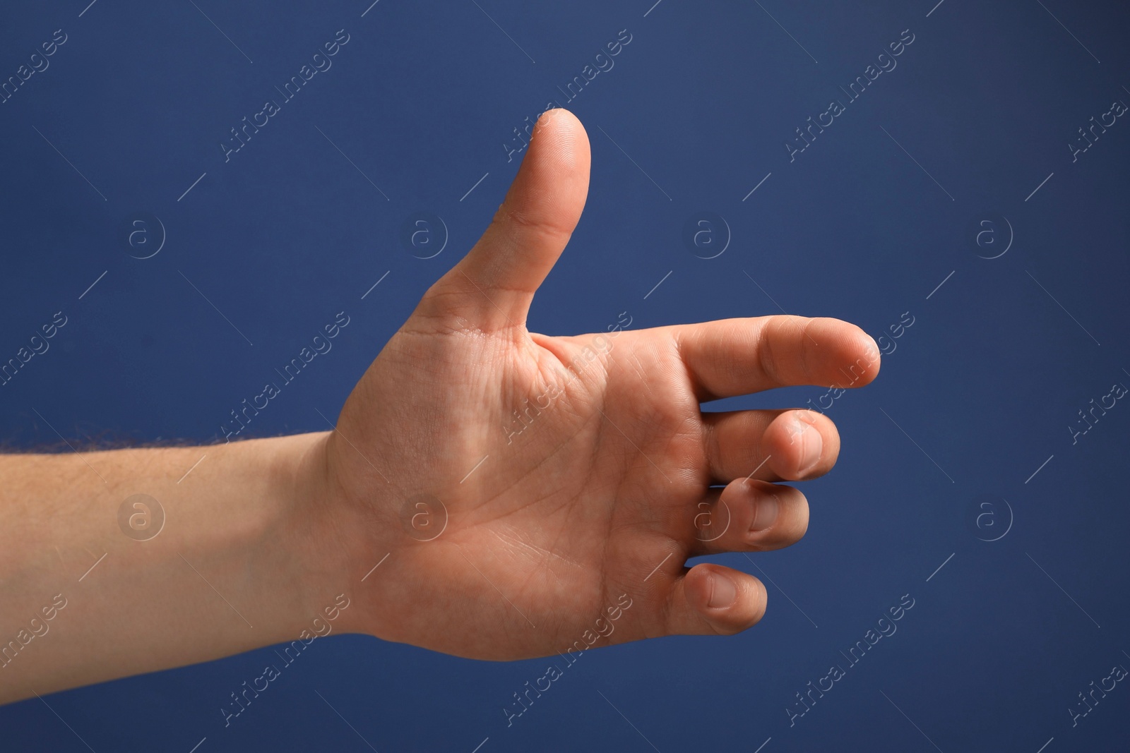 Photo of Man holding something in hand on blue background, closeup