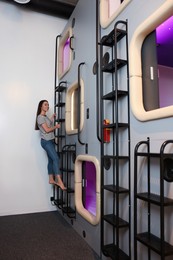 Happy young woman climbing up ladder to capsule in pod hostel