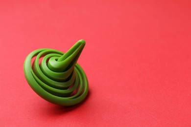 Photo of One green spinning top on red background, space for text