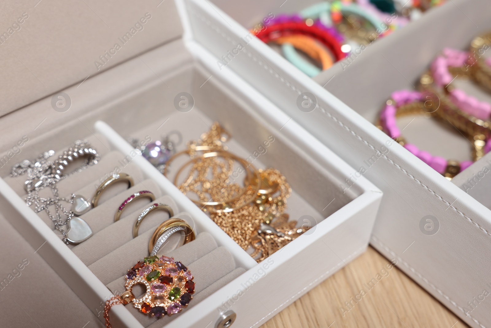 Photo of Jewelry boxes with stylish bracelets and other accessories on wooden table, closeup