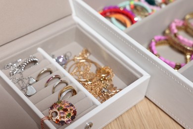 Jewelry boxes with stylish bracelets and other accessories on wooden table, closeup