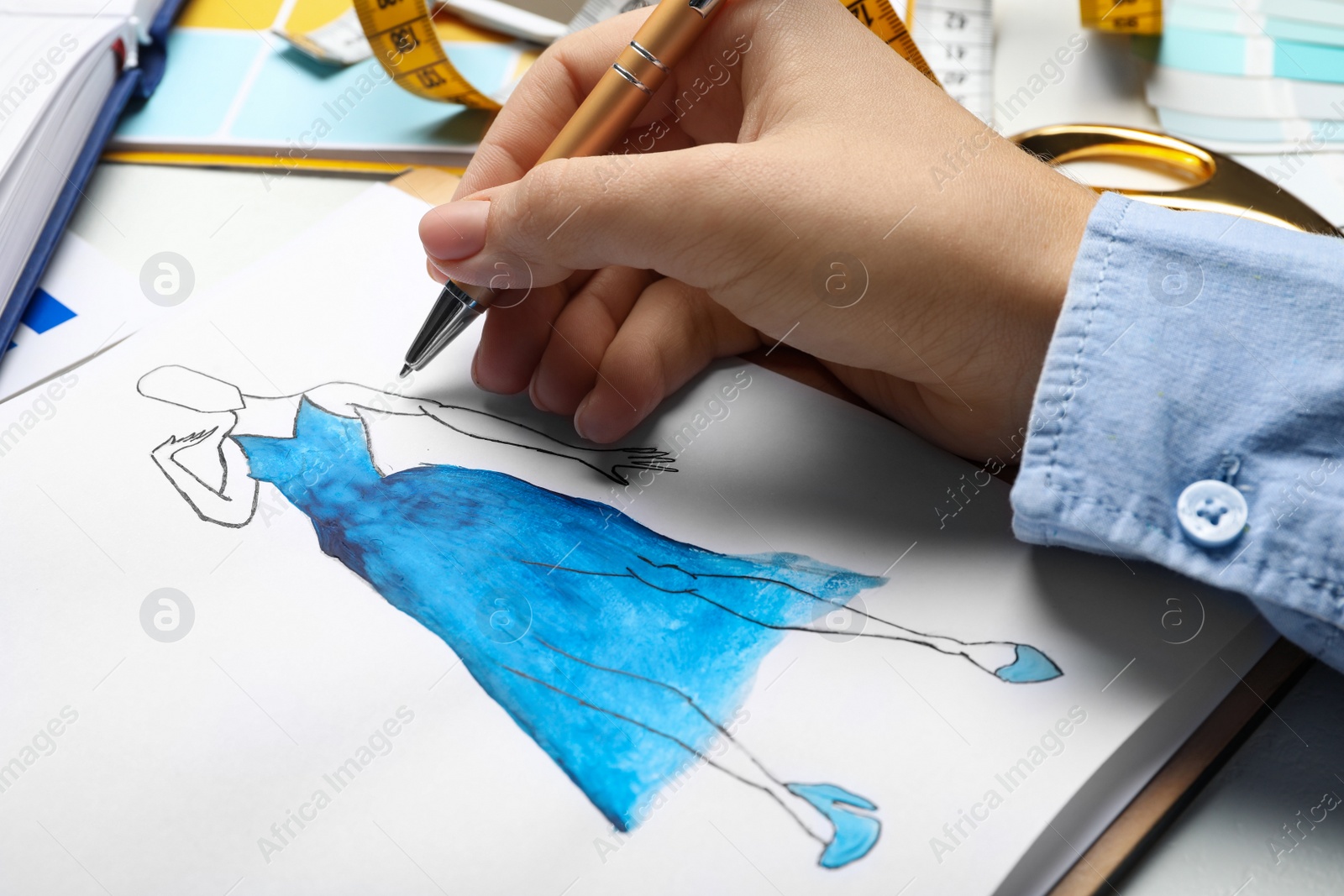 Photo of Fashion designer drawing dress at table, closeup