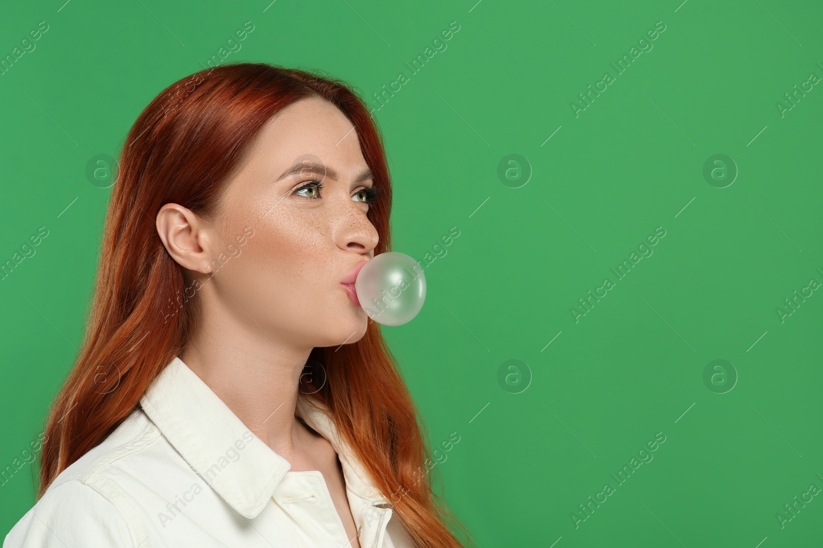 Photo of Beautiful woman blowing bubble gum on green background. Space for text
