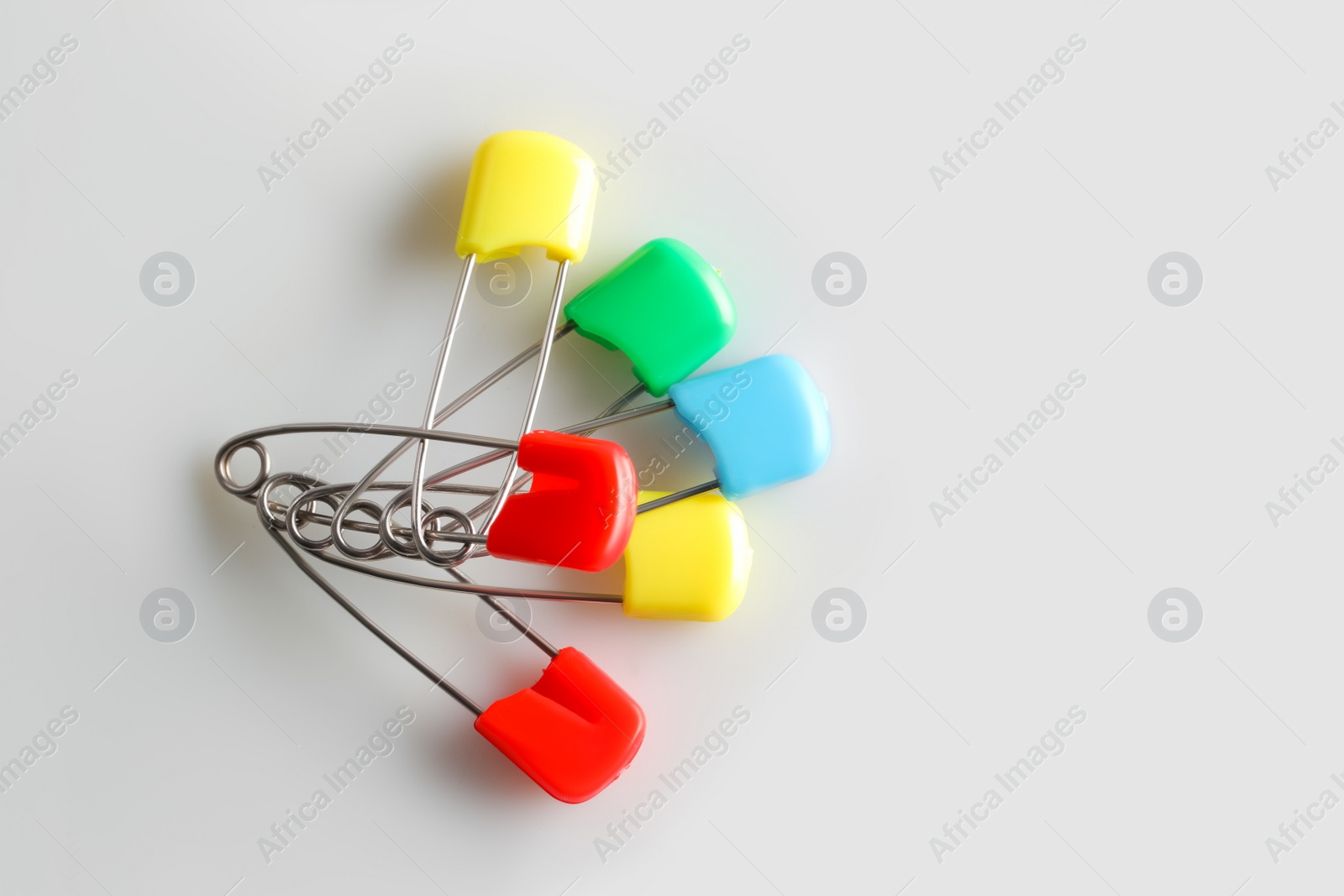 Photo of Colorful safety pins on white background, flat lay. Space for text