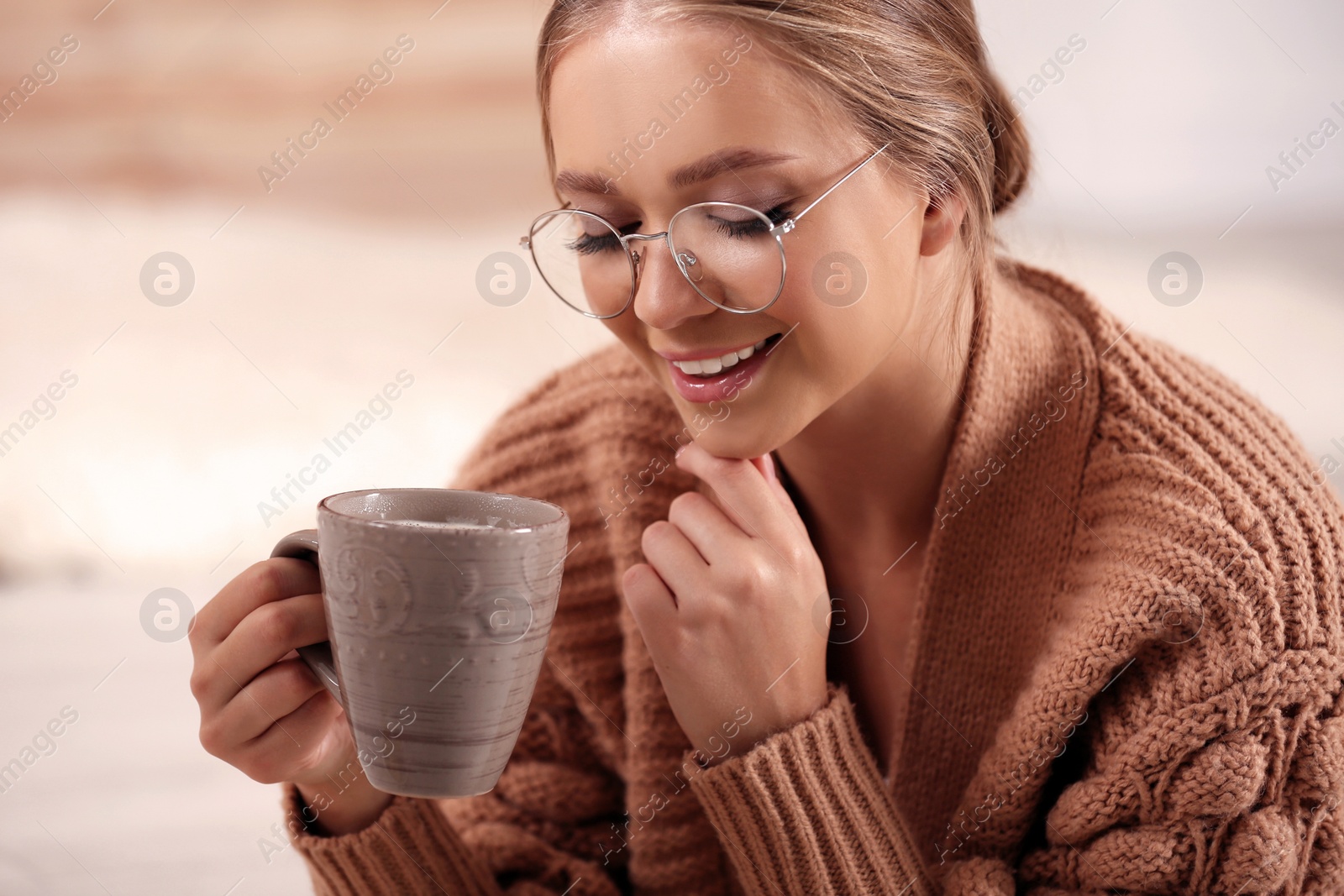 Photo of Beautiful young woman with cup of hot drink at home. Winter atmosphere