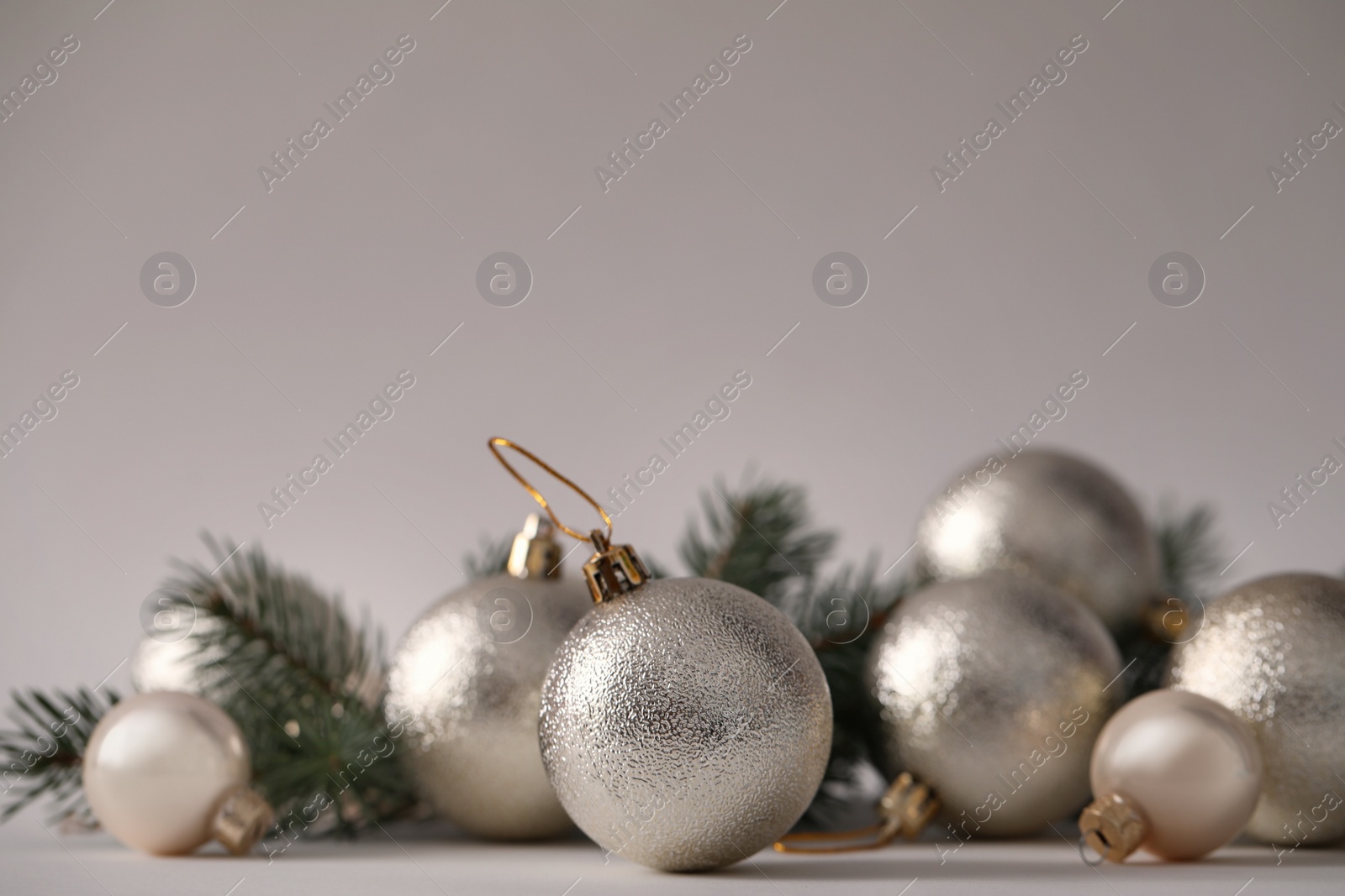 Photo of Beautiful Christmas balls and fir branches on grey background. Space for text