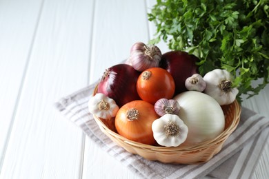 Photo of Fresh raw garlic, onions and parsley on white wooden table. Space for text