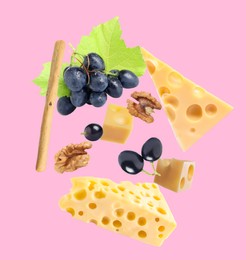 Image of Cheese, breadstick, grapes and walnut falling against pale pink background