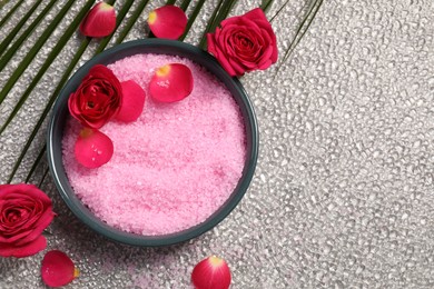 Photo of Natural sea salt in bowl, rose flowers and petals on grey textured table, flat lay. Space for text