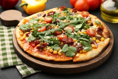 Photo of Delicious vegetarian pizza with cheese, vegetables and greens on black table, closeup