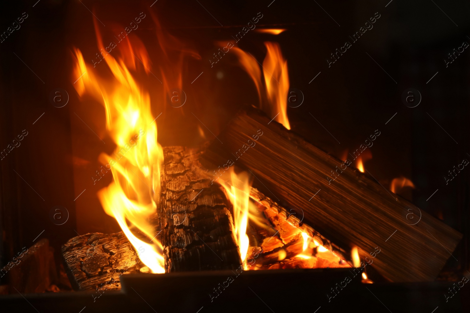 Photo of Fireplace with burning wood, closeup view. Winter vacation