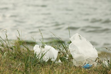 Photo of Plastic garbage scattered on grass near river