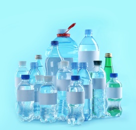 Photo of Different bottles of pure water with blank tags on color background