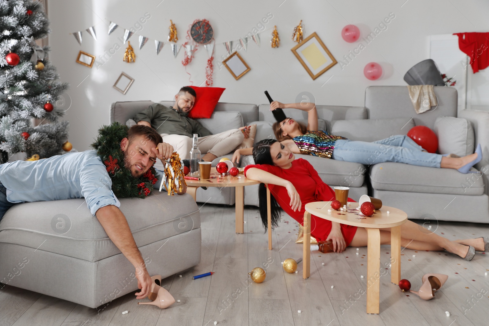 Photo of Friends suffering from hangover in messy room after New Year party